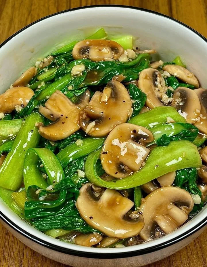 Plate of sautéed mushrooms and bok choy garnished with herbs