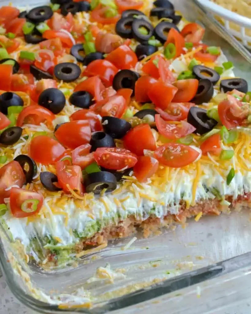 Delicious and colorful 7 layer dip served in a glass bowl