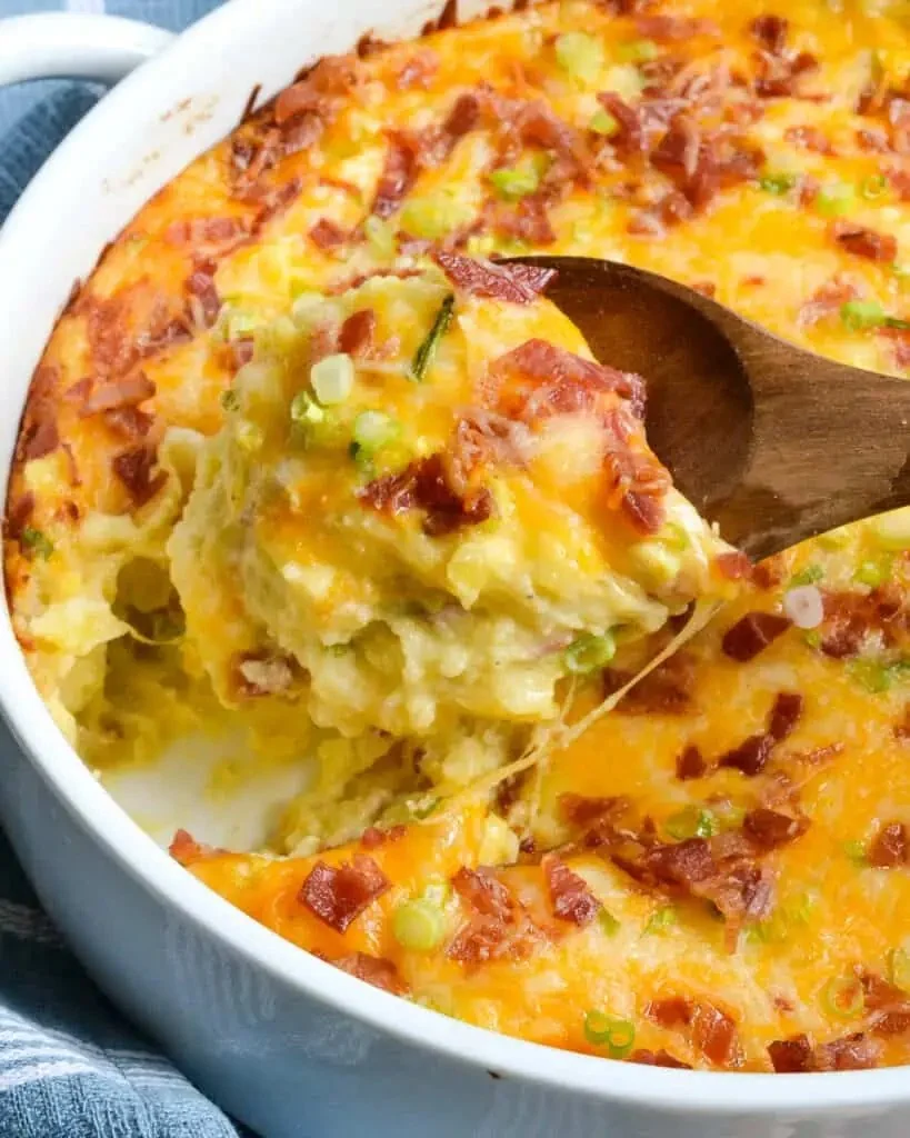 Twice Baked Potato Casserole topped with cheese and herbs in a baking dish