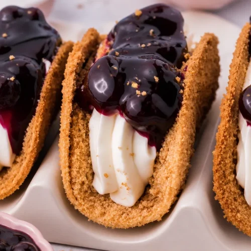 Delicious blueberry cheesecake tacos served on a plate with fresh blueberries.