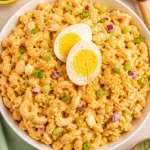 Creamy deviled egg pasta salad in a bowl garnished with herbs