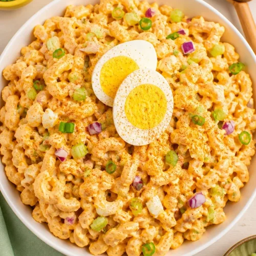 Creamy deviled egg pasta salad in a bowl garnished with herbs